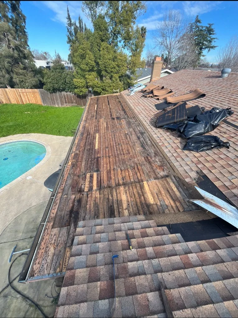 Wide view of an asphalt roof with shingles removed to expose the wood roof deck